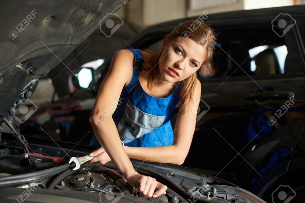 92684193-close-up-of-brunette-female-mechanics-repairing-or-inspecting-a-car-and-holds-a-spanner-in-her-hand-.jpg